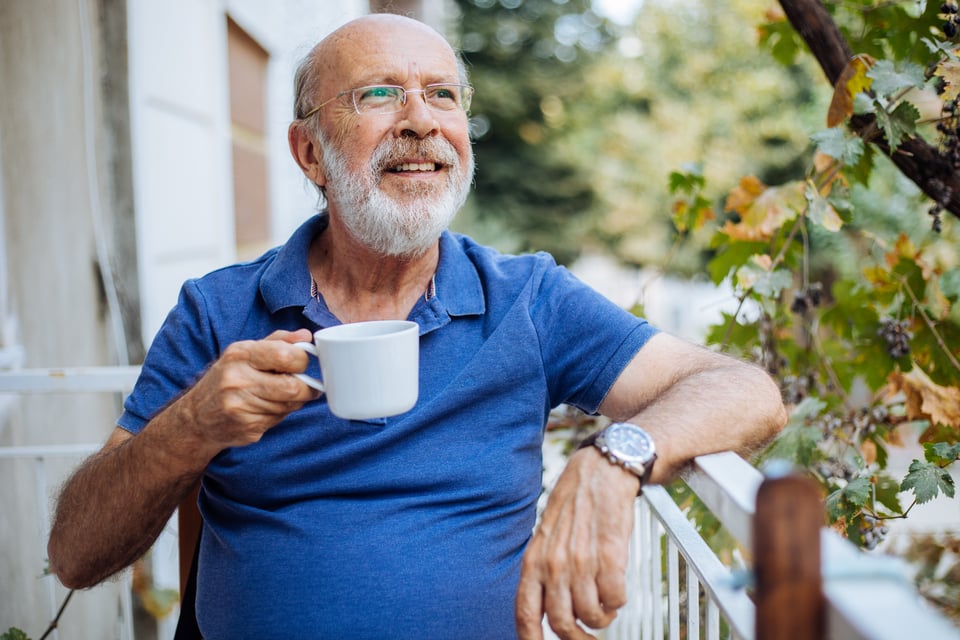 An elderly man enjoying a cup of coffee outside