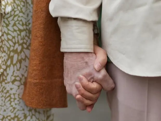 Two elderly people holding hands