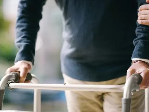 Elderly man using a walker to walk