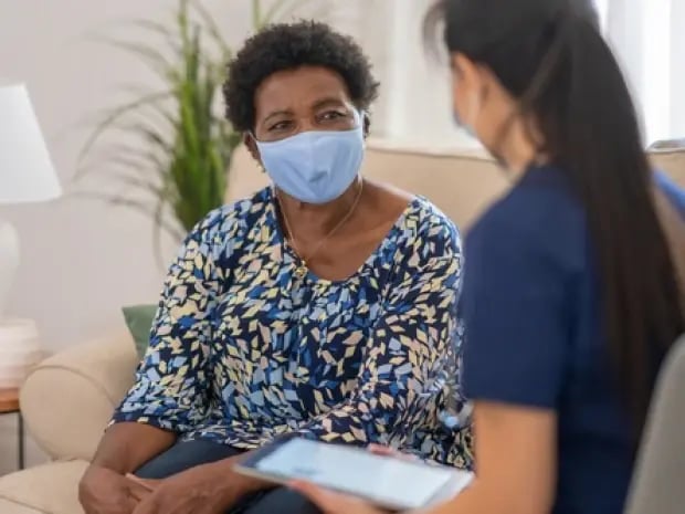 Woman and caregiver talking on couch