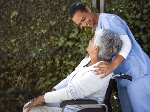 Caregiver pushing elderly patient's wheelchair
