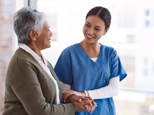 Caregiver and elderly woman walking side by side