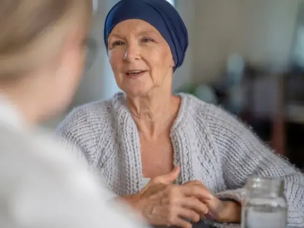 An elderly woman with cancer speaking to a person