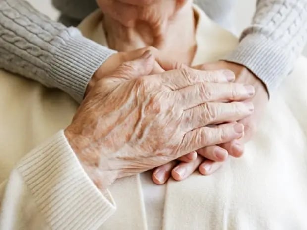 Elderly woman and person holding hands