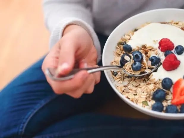 Person eating oatmeal with yogurt and fruit